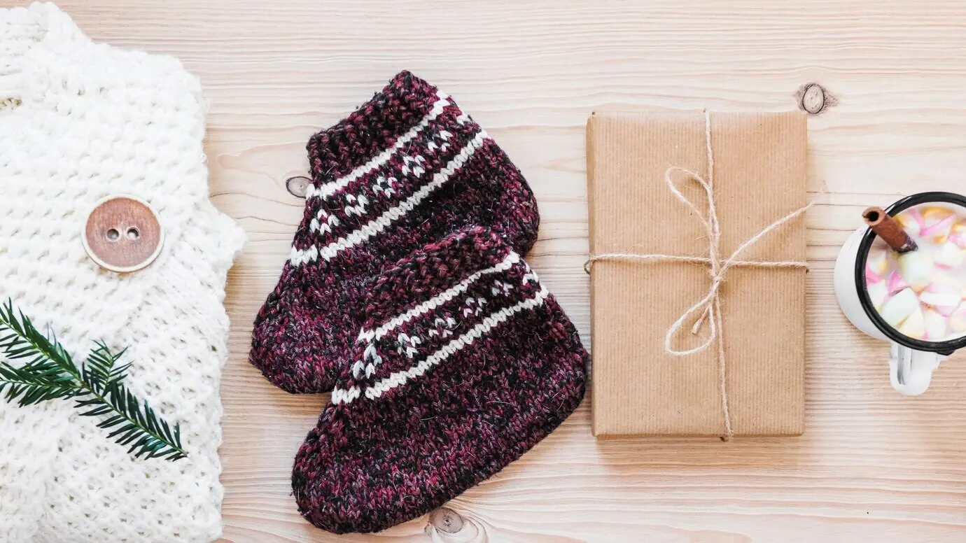 Geschenk in der Nähe von warmer Kleidung und heißer Schokolade